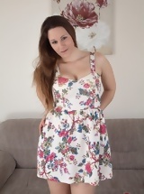 Hairy woman in floral dress and black shoes poses on couch